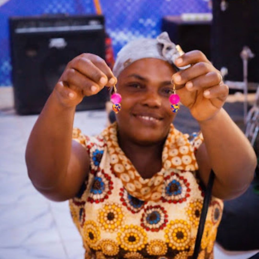 Smiling woman holding up a pair of handmade earrings